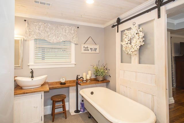 bathroom with a washtub, hardwood / wood-style floors, vanity, and ornamental molding