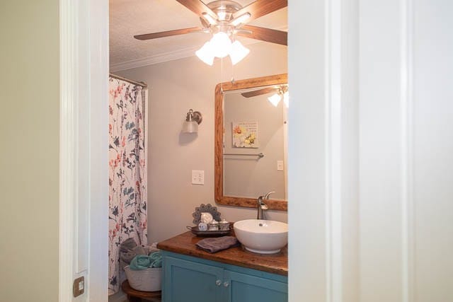 bathroom with vanity, a shower with shower curtain, ceiling fan, ornamental molding, and a textured ceiling