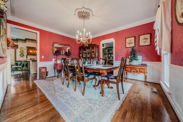 dining room featuring wood-type flooring, ornamental molding, and a notable chandelier