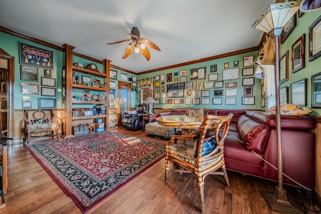 living area featuring wood-type flooring, ceiling fan, and crown molding