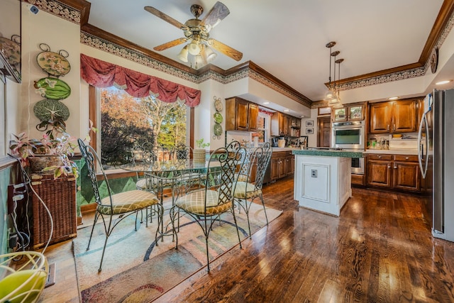 kitchen featuring ceiling fan, dark hardwood / wood-style flooring, crown molding, a kitchen island, and appliances with stainless steel finishes