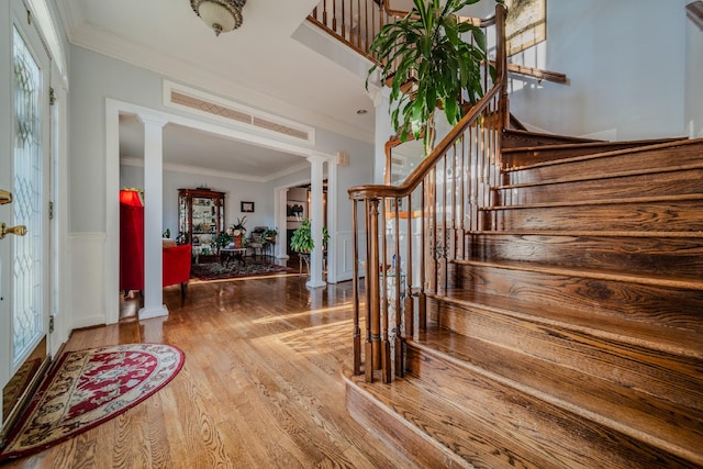 entryway featuring ornate columns, hardwood / wood-style floors, and ornamental molding