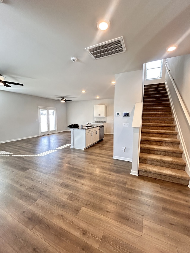 unfurnished living room with ceiling fan, sink, and wood-type flooring