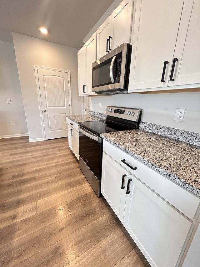 kitchen featuring light stone counters, stainless steel appliances, white cabinetry, and light hardwood / wood-style flooring