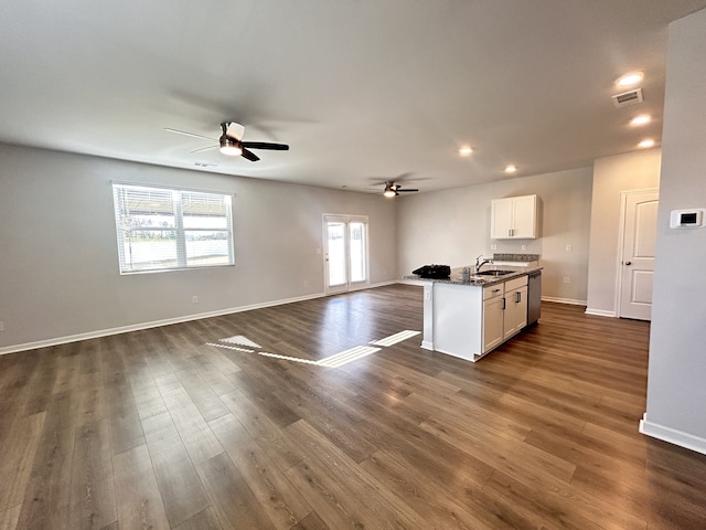 kitchen featuring dark stone counters, a center island with sink, dishwasher, white cabinets, and dark hardwood / wood-style floors