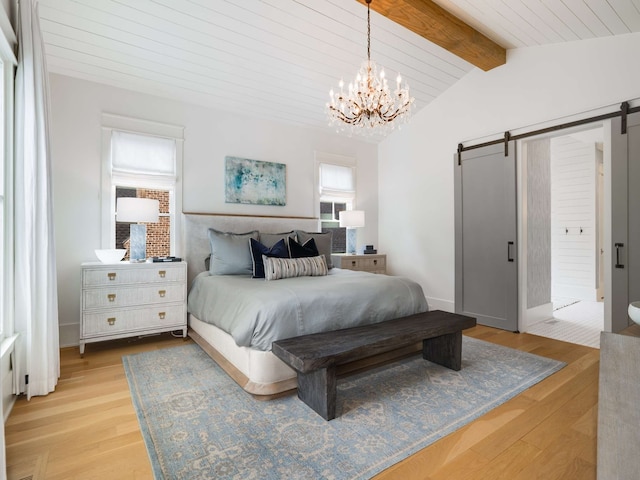 bedroom with a barn door, a chandelier, lofted ceiling with beams, and light wood-type flooring