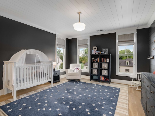 bedroom with light hardwood / wood-style floors, wooden ceiling, and multiple windows