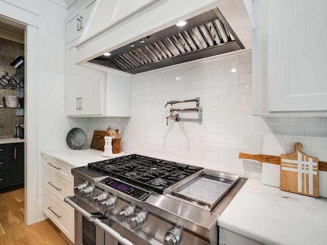 kitchen with decorative backsplash, custom exhaust hood, light hardwood / wood-style flooring, high end stainless steel range, and white cabinetry