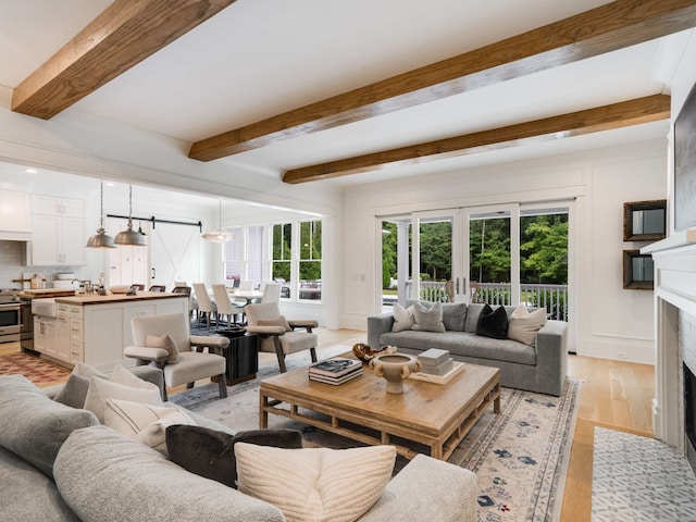 living room with beamed ceiling, french doors, a high end fireplace, and light hardwood / wood-style flooring