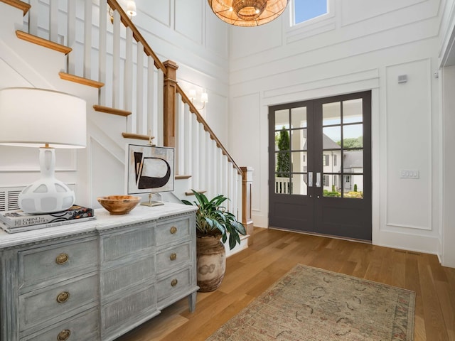 foyer entrance featuring wood-type flooring, a high ceiling, and french doors