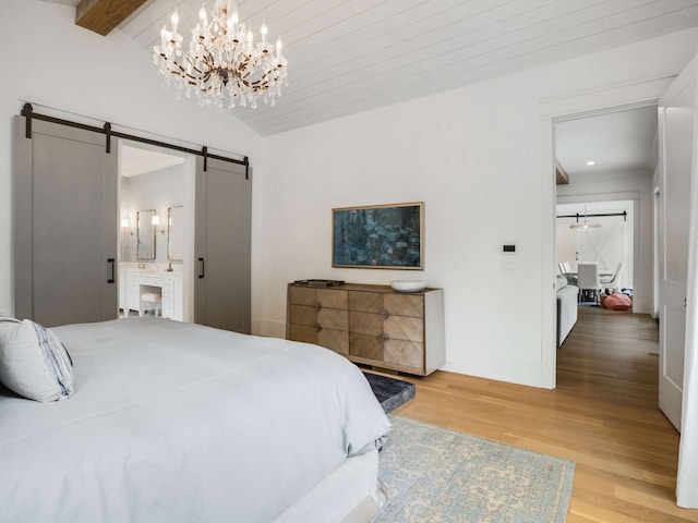 bedroom with ensuite bath, a barn door, hardwood / wood-style flooring, a notable chandelier, and vaulted ceiling with beams