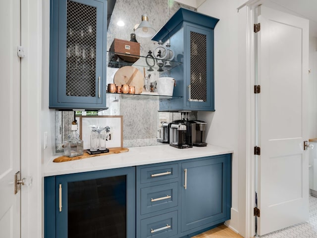 bar featuring blue cabinetry, decorative backsplash, and wine cooler