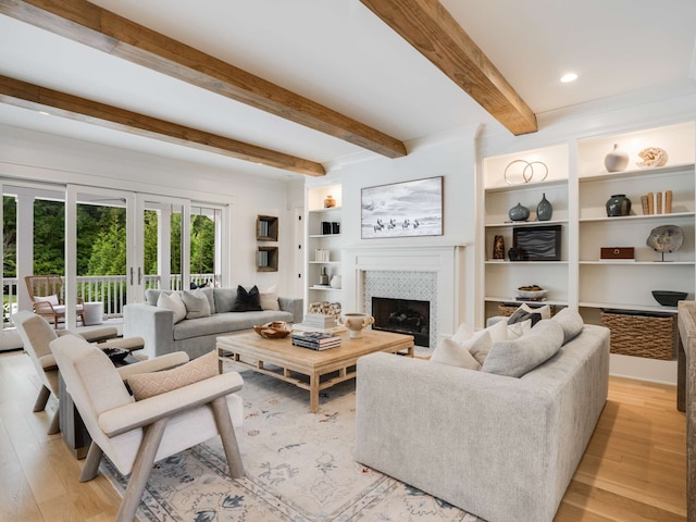 living room with beam ceiling, a fireplace, light hardwood / wood-style flooring, and french doors