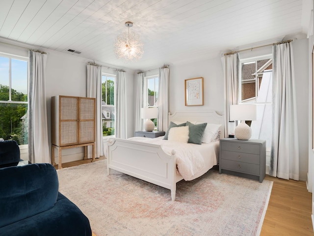 bedroom featuring a chandelier, light wood-type flooring, wood ceiling, and multiple windows