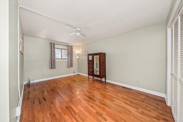 unfurnished bedroom with a textured ceiling, ceiling fan, a closet, and hardwood / wood-style floors