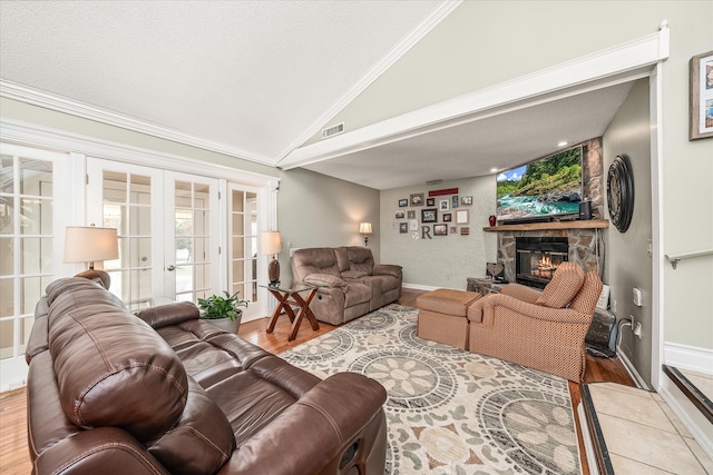 living room with light hardwood / wood-style floors, french doors, vaulted ceiling, and a fireplace