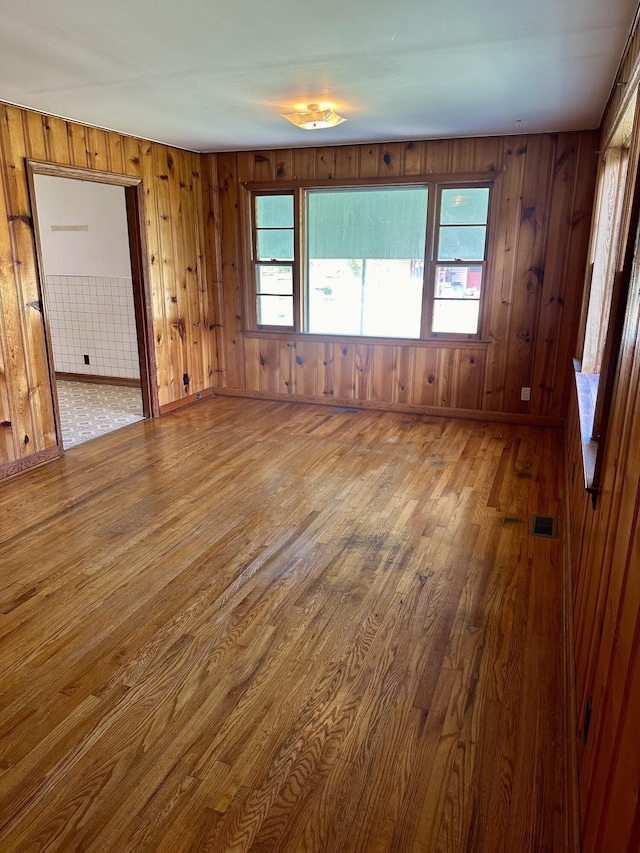 spare room with hardwood / wood-style floors and wood walls