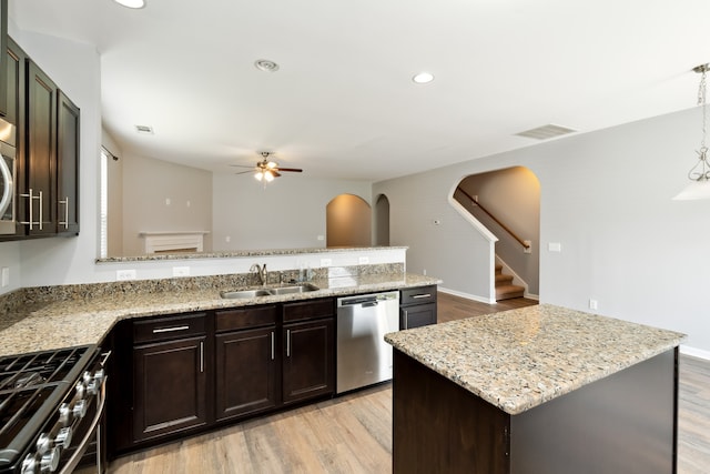 kitchen with ceiling fan, sink, a center island, stainless steel appliances, and light hardwood / wood-style floors