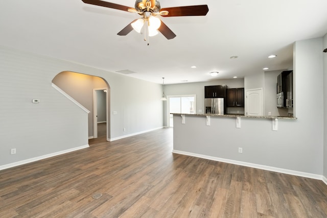 unfurnished living room featuring ceiling fan and dark hardwood / wood-style flooring