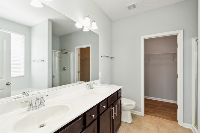 bathroom featuring toilet, tile patterned flooring, vanity, and walk in shower