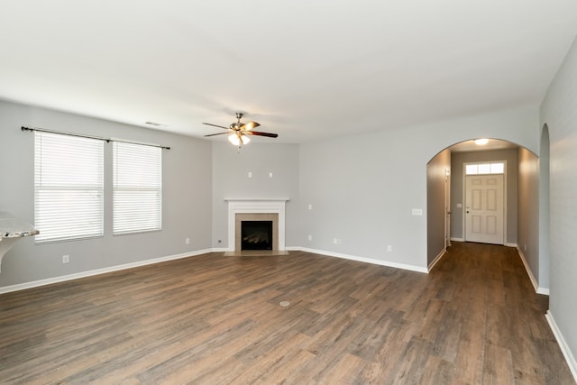 unfurnished living room with dark hardwood / wood-style flooring and ceiling fan