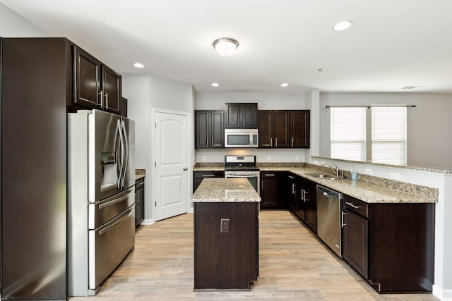 kitchen with a center island, sink, light hardwood / wood-style flooring, dark brown cabinetry, and stainless steel appliances