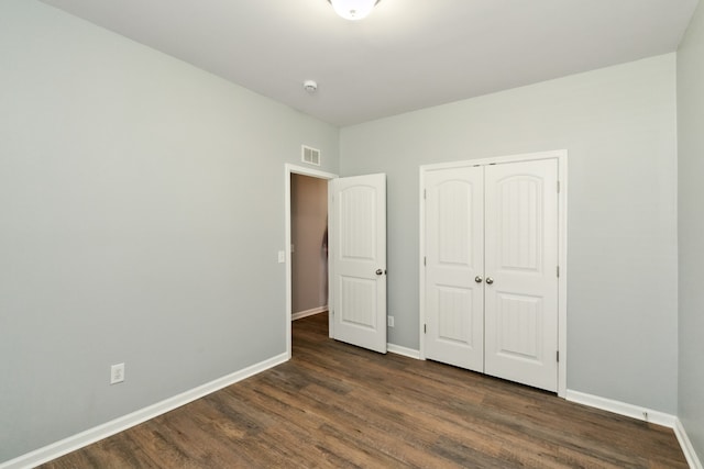 unfurnished bedroom with dark wood-type flooring and a closet