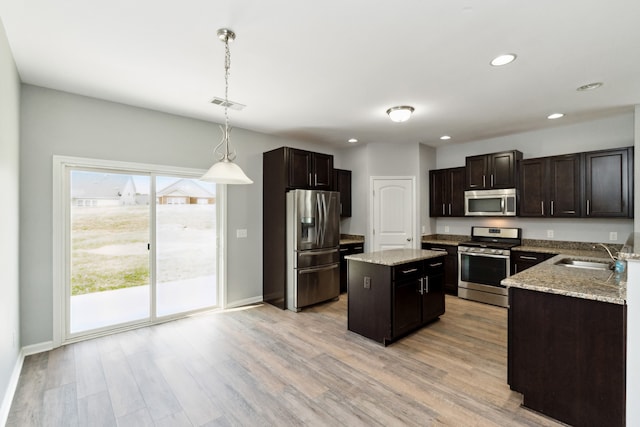 kitchen featuring decorative light fixtures, a center island, light wood-type flooring, and stainless steel appliances