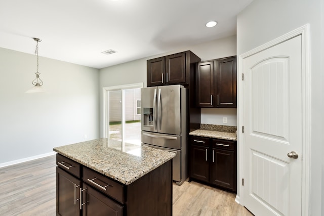 kitchen with stainless steel fridge, dark brown cabinets, pendant lighting, and light hardwood / wood-style floors