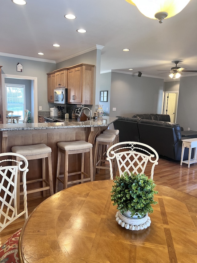 kitchen featuring kitchen peninsula, ceiling fan, crown molding, sink, and hardwood / wood-style flooring