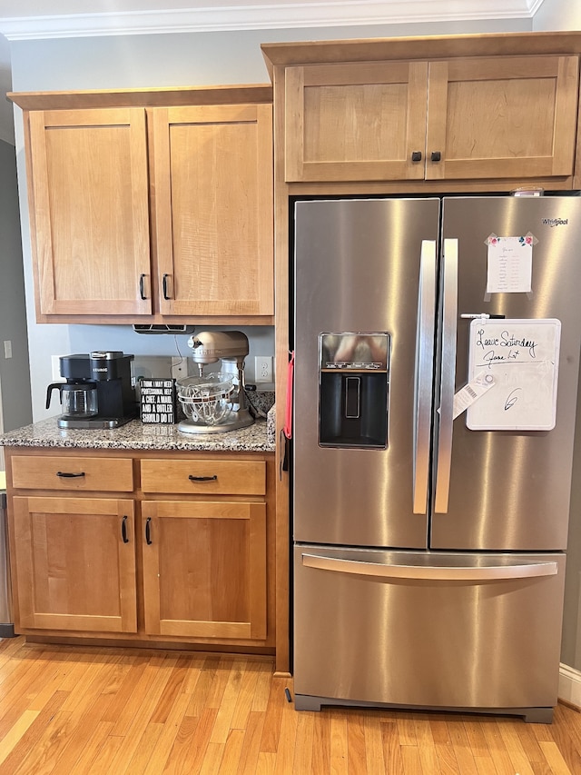 kitchen featuring stainless steel refrigerator with ice dispenser, light wood-type flooring, light stone counters, and ornamental molding