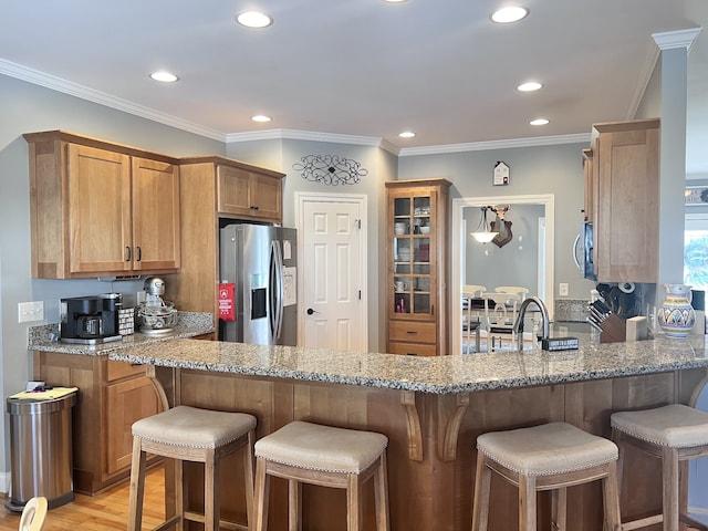 kitchen with a kitchen breakfast bar, light stone countertops, kitchen peninsula, and stainless steel appliances