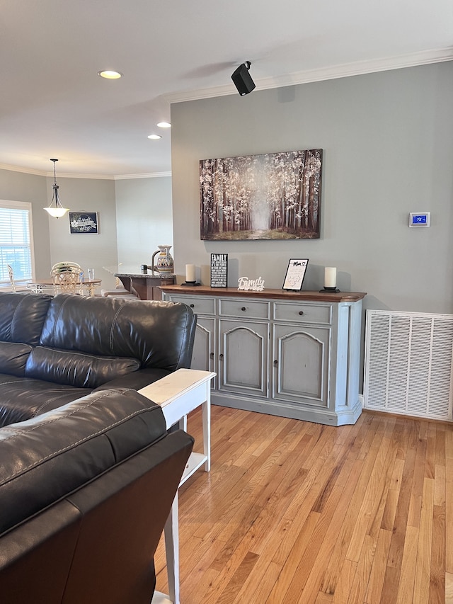 living room with light wood-type flooring and crown molding