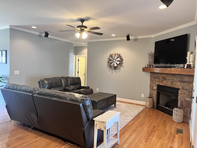 living room featuring a stone fireplace, ornamental molding, and light hardwood / wood-style flooring