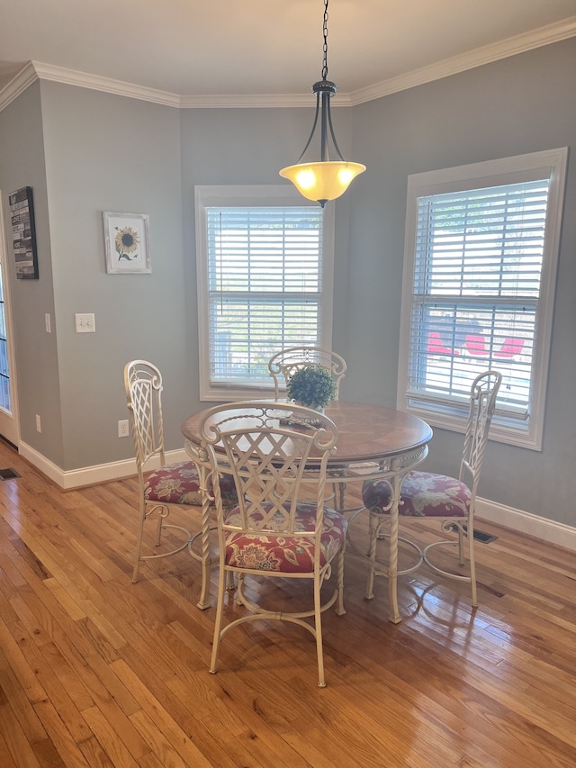 dining room with crown molding, a wealth of natural light, and light hardwood / wood-style flooring