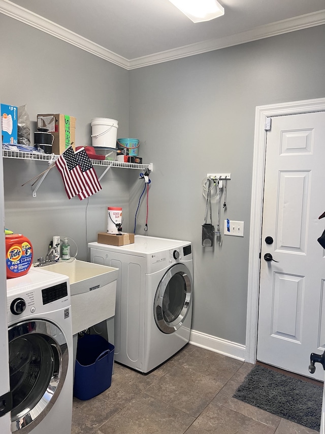 laundry area featuring dark tile patterned flooring, washer and dryer, sink, and crown molding