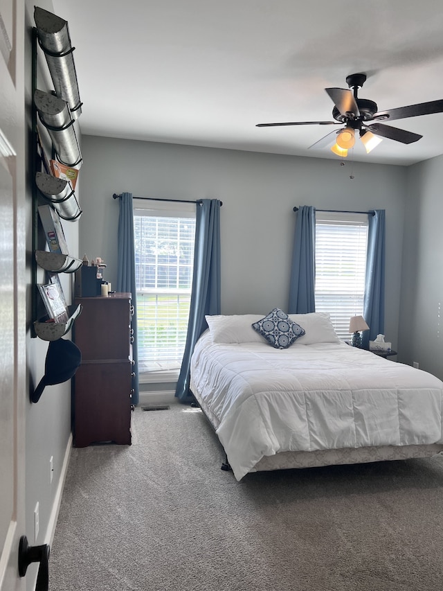 carpeted bedroom featuring multiple windows and ceiling fan