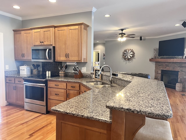 kitchen featuring kitchen peninsula, sink, light wood-type flooring, and appliances with stainless steel finishes