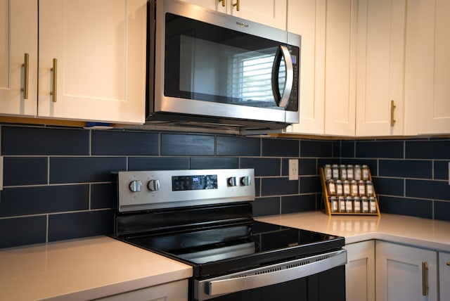 kitchen featuring stainless steel appliances, white cabinetry, and tasteful backsplash