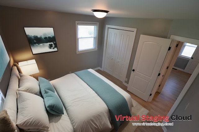 bedroom with hardwood / wood-style floors, lofted ceiling, and a closet