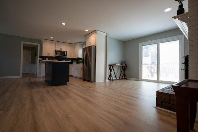 kitchen with white cabinetry, a center island, stainless steel appliances, and light hardwood / wood-style floors