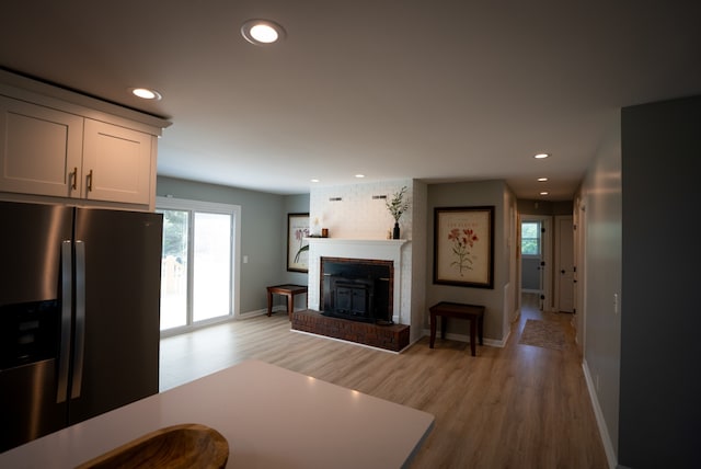 living room with light hardwood / wood-style floors and a brick fireplace