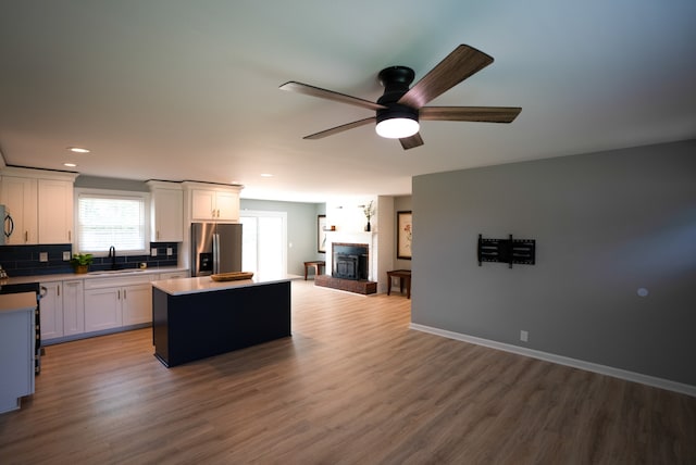 kitchen featuring a kitchen island, sink, wood-type flooring, and stainless steel refrigerator with ice dispenser