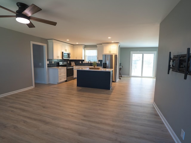 kitchen featuring white cabinets, appliances with stainless steel finishes, hardwood / wood-style flooring, and a kitchen island