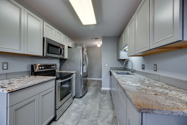 kitchen featuring light stone countertops, appliances with stainless steel finishes, and sink