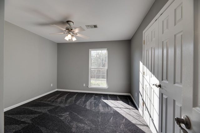 spare room with dark colored carpet and ceiling fan