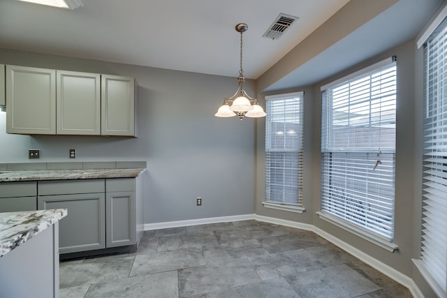 kitchen featuring light stone countertops, decorative light fixtures, and an inviting chandelier