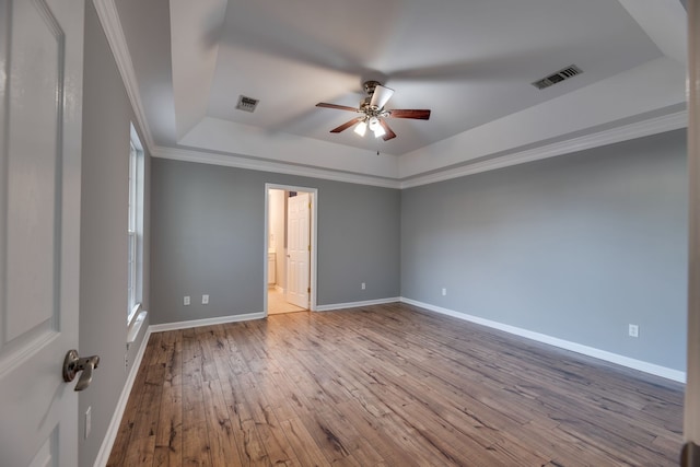 unfurnished room with light wood-type flooring, a tray ceiling, ceiling fan, and ornamental molding