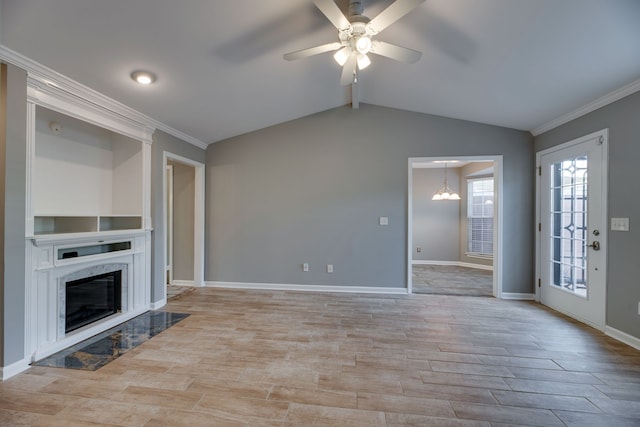 unfurnished living room featuring light hardwood / wood-style flooring, a high end fireplace, crown molding, vaulted ceiling, and ceiling fan with notable chandelier