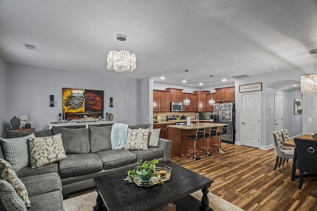 living room with dark wood-type flooring, a chandelier, and sink